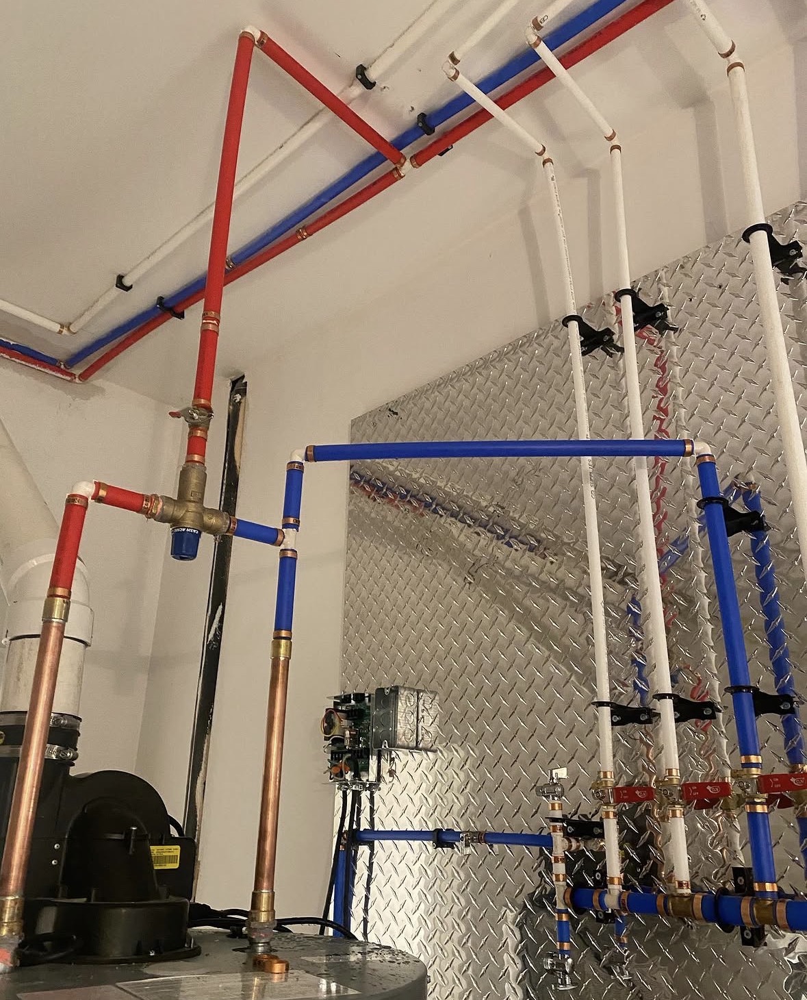 Neatly run PEX and copper water lines with a manifold in a mechanical room
